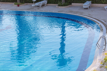 Reflection of a palm tree in the blue water of the pool.