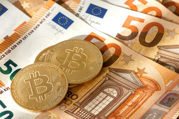 Pile of bitcoin coins over 50 euros banknotes background. New decentralized monetary standard.
