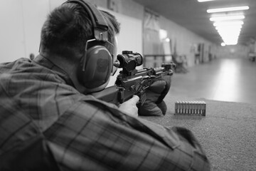 Shooting and rifles in a shooting range at a target, a man aims from a rifle at a target.  Black...