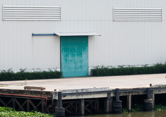 White warehouse building with green door at port