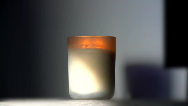 Cozy warm white and orange candle burning in soft lighted room, selective focus