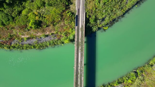 Top down shot of grassy abandoned railway track on bridge over calm clean river