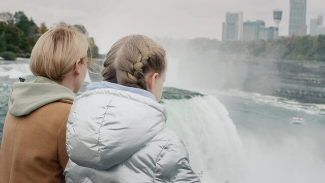 A woman with a child together admires the breathtaking spectacle of Niagara Falls