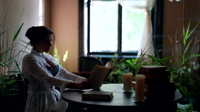 beautiful dreamy woman is reading favorite book in romantic vintage room of old library in noble estate