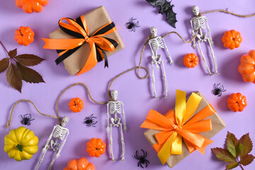Various Halloween accessories with skeletons, spiders, gifts and pumpkins on a purple background with a place for text. A place to copy. Flat position, top view