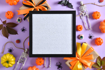 A mock-up of a Halloween board with skeletons, spiders, gifts and pumpkins on a purple background with a place for text. A place to copy. Flat position, top view