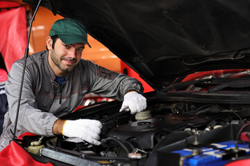 Fototapeta na wymiar Professional mechanic working on the engine of the car in the garage. Car repair service.