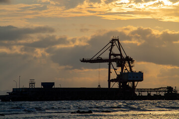Fototapeta na wymiar Heavy equipment crane silhouette on twilight clouds background