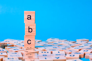 English alphabet made of square wooden tiles with the English alphabet scattered on blue...