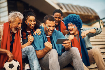 Group of excited fans watching live broadcast of soccer match on smart phone.