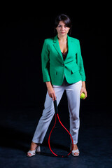 Woman in green jacket with tennis ball on black background