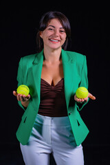 Woman in green jacket with tennis ball on black background