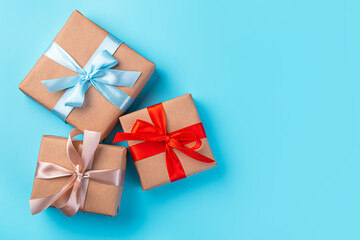 Gift boxes with colored ribbons on a blue background. Top view, horizontal