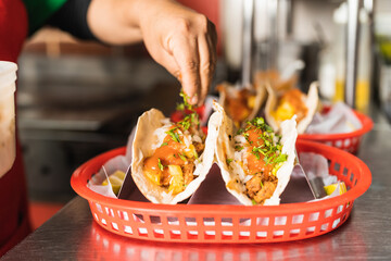 Chef adding herbs to a mexican tacos ready-to-eat in a restaurant