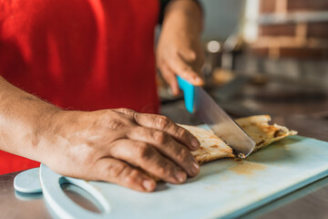 Cook cutting a taco in half in a kitchen