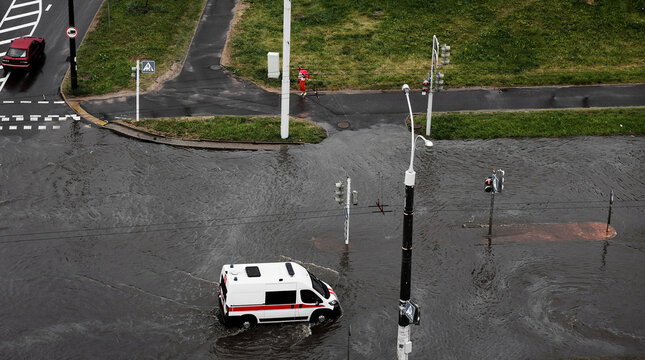ambulance is driving along a flooded road - Powered by Adobe