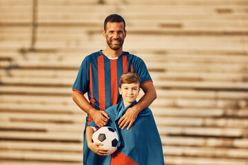 Happy football fan and his son wearing their favorite team's jerseys while going on match and...