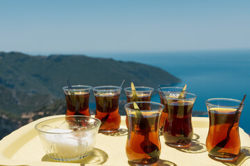 Two crystal glasses of black tea with saucers on blue tray outdoors in garden. Sunny scene still life on wooden chair. Traditional Azerbaijani tea serving, Novruz or Ramadan celebration, copy space