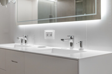 Fototapeta na wymiar Brand new water taps and double sink in luxury bathroom. Modern mirror with lightning.