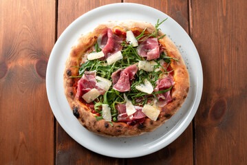 Deliziosa pizza condita con prosciutto crudo, rucola, mozzarella, sugo e scaglie di grana, cibo italiano
