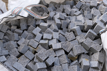 Pile of granite paving stones in a large bag on road construction. Cobblestone ready to use for building a road. Close up.