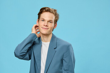 portrait of a pleasant handsome young man in a gray jacket straightening his red hair