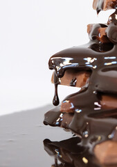 chocolate sauce flowing over chocolate pieces on white background