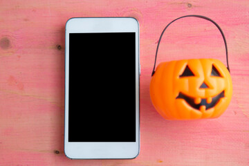 mobile phone, and pumpkin on pink background. halloween party concept