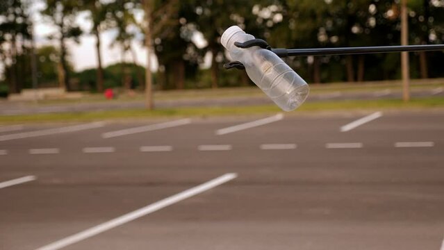 Close-up of a garbage collection tongs with a plastic bottle in the city. The concept of garbage collection and environmental protection.