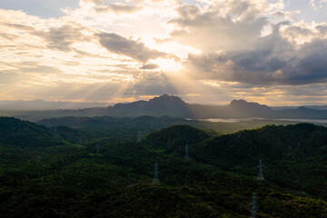 Aerial view Transmission tower in green forest and beautiful sunset. Energy and environment concept. High voltage power poles. Pang Puay, Mae Moh, Lampang, Thailand.