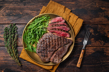 BBQ dinner with top sirloin beef steak and salad on a plate. Wooden background. Top view
