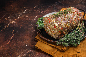 Rolled meat pork roulade with rosemary and thyme. Dark background. Top view. Copy space