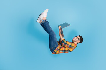 Full length profile portrait of impressed falling man use netbook isolated on blue color background