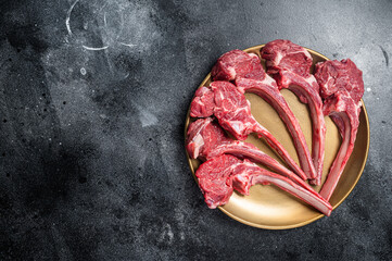 Lamb chop rib steak, raw mutton meat cutlet in golden plate. Black background. Top view. Copy space