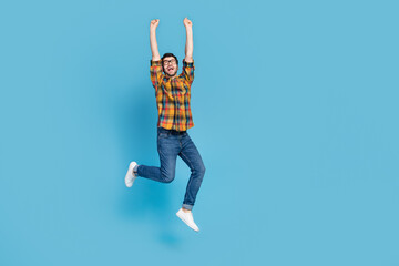 Fototapeta na wymiar Full body photo of satisfied astonished person jumping raise fists accomplishment isolated on blue color background