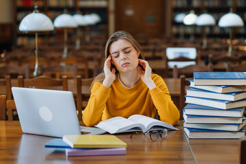 exhausted student sitting at a table in the library, preparing f