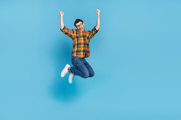 Full length photo of crazy lucky person raise fists triumph jumping isolated on blue color background - obrazy, fototapety, plakaty