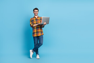 Full body photo of cheerful young man hold use wireless netbook empty space isolated on blue color...