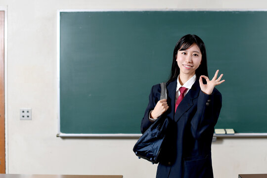 黒板の前で制服を着た笑顔の女子学生