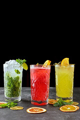 Different lemonades on a black background, on gray concrete