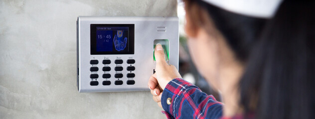 Woman employee scanning fingerprint on the machine to record working time.
