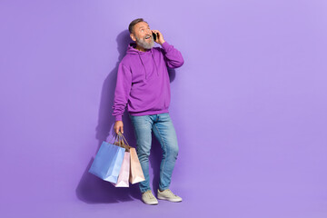 Fototapeta Full size photo of handsome senior satisfied man dressed purple hoodie jeans talking fast speed 5g isolated on violet color background obraz