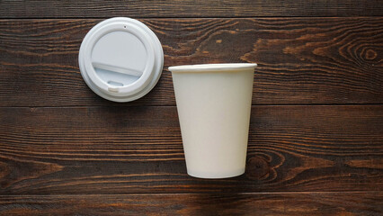 White paper cup and plastic lid on dark wooden table top view