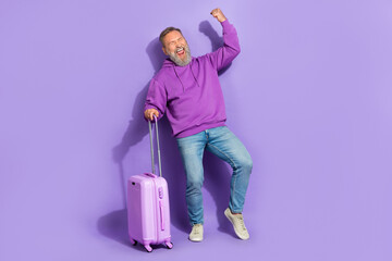 Full size photo of handsome senior satisfied man dressed purple sweatshirt jeans scream yeah fist up isolated on violet color background