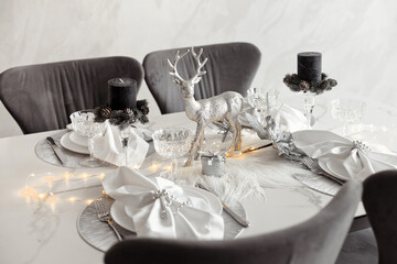 Festive monochrome table setting in gray and silver colors for winter holidays dinner in modern interior