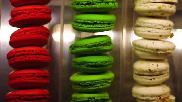 Scrolling closeup view of vibrant red, green, and cream French macaron pastries