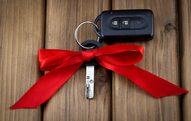 Close-up view of car keys with red bow as present on  wooden background
