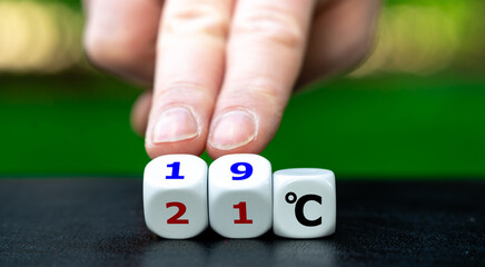 Hand turns dice and changes the expression "21 degrees Celsius" to "19 degrees Celsius". Symbol for lowering the temperature in offices to reduce the energy consumption.