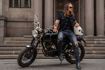Plakat Portrait of guy looking like macho posing with motorbike outdoors.
