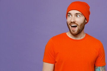 Young shocked calm surprised stylish man 20s he wear red hat t-shirt looking aside on workspace area mock up isolated on plain pastel light purple background studio portrait. People lifestyle concept.